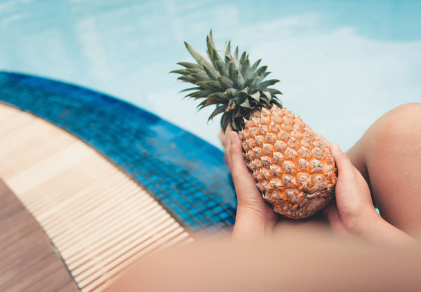 Summer concept, Close up portrait of woman is holding pineapple at poolside. - Valokuva, kuva
