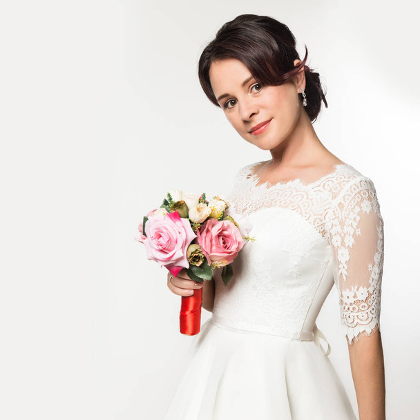 elegant bride on a light background. Beautiful wedding bouquet in a bride hands. free space for your text - Photo, Image