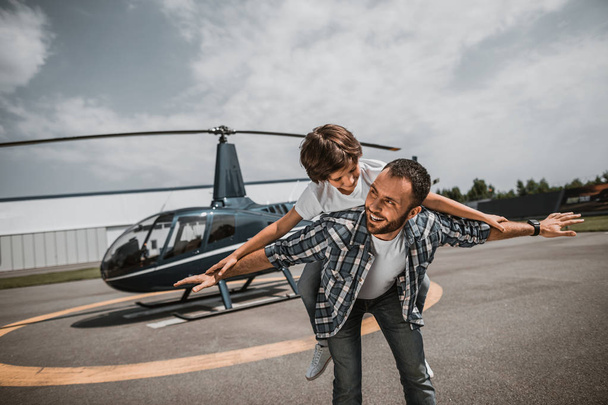 Glad dad playing with son near helicopter - Foto, imagen
