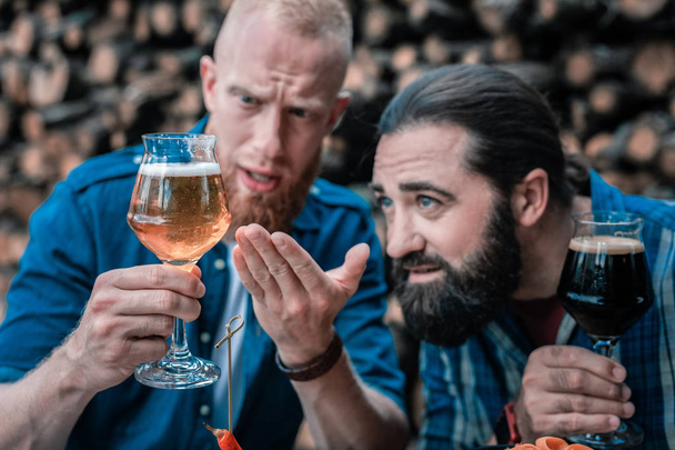 Two bearded men looking at new type of light craft beer - Foto, afbeelding