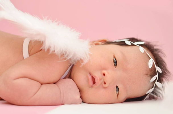 kleine süße asiatische Mädchen Baby auf dem Boden liegend mit Engelsflügel und schöne Stirnband mit leeren Kopierraum - Foto, Bild