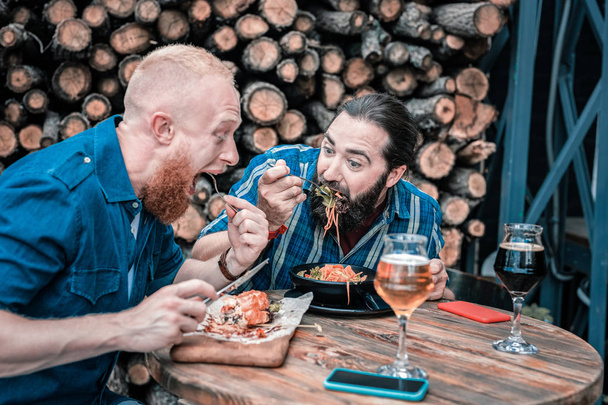 Two hungry men feeling good while having tasty dinner - Valokuva, kuva