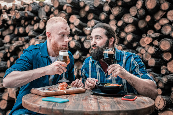 Two bearded mature men enjoying taste of delicious craft beer - Fotó, kép