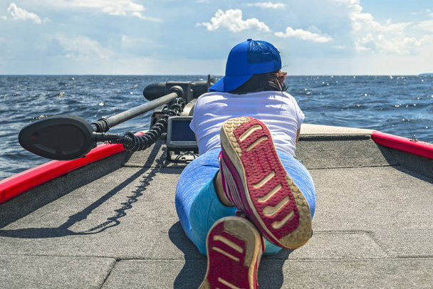 Молодая женщина лежит на рыбацкой лодке с рыбоискателем, эхолотом, гидролокатором и сканером структуры на борту
 - Фото, изображение