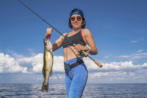 Onnellinen kalastaja nainen kuha kala pokaali veneessä
 - Valokuva, kuva