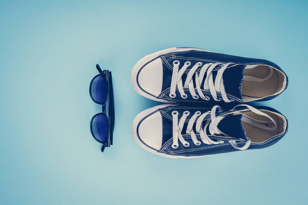 Sapatilhas e óculos em um fundo azul
 - Foto, Imagem