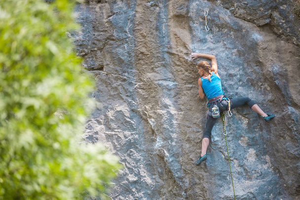De klimmer is opleiding te beklimmen van de rots. Een sterke meisje overwint een moeilijke klimmen route. Actieve levensstijl. Extreme hobby. Een vrouw gaat voor sporten in de natuur. - Foto, afbeelding
