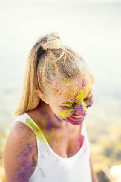 The festival of Holi.The joy and happiness. Paint on the face. Blonde girl. The festival of Holi. The joy and happiness. Paint on the face. Girl the blonde . The smile on her face, happiness - Fotoğraf, Görsel