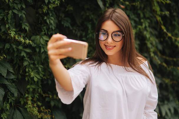 Beautiful girl make a selfie on smart phone outside - Zdjęcie, obraz
