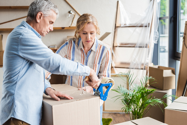 focused senior couple packing cardboard boxes while moving home - Foto, immagini
