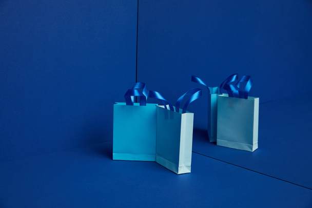 close up view of arranged paper shopping bags with mirror reflection on blue background - Foto, Imagem