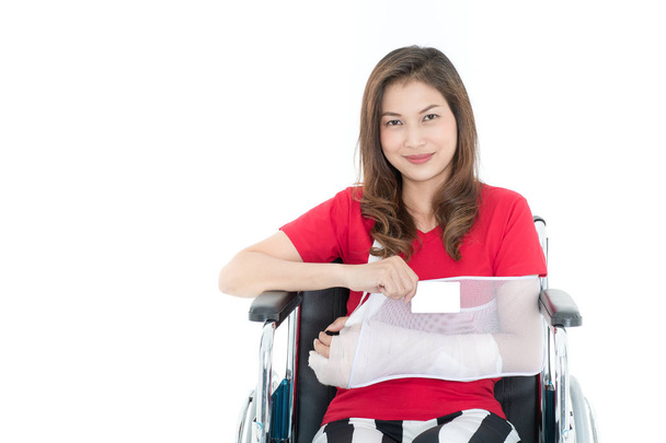 Zlomeny rameno Asijské žena paže praku sponzoroval v její ruce, které sedí na invalidním vozíku a zobrazení prázdné vysmívat se karty. Nápady na nehodě zranění a zdravotní péči. Studio záběr na bílém pozadí - Fotografie, Obrázek