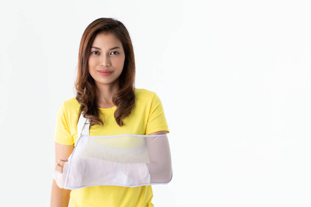 Arm gebrochen asiatische Frau mit Armschlinge an der Hand gestützt, Konzept für Verletzungen durch Unfall und Gesundheitsversorgung. Studioaufnahme auf weißem Hintergrund. - Foto, Bild