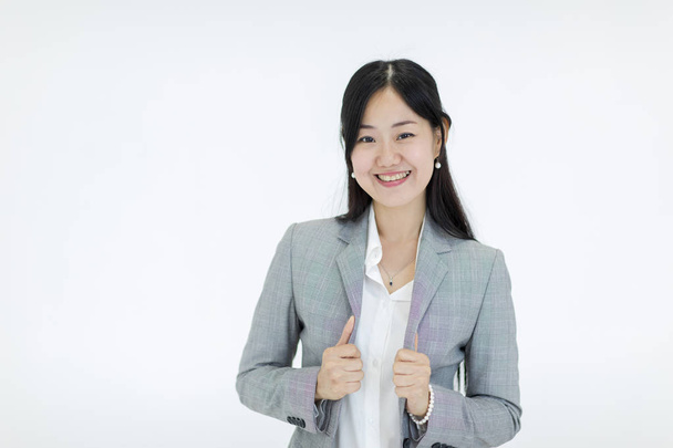 Mooi Aziatisch meisje met lang haar ziet er goed smil dragen een pak. Staande op een witte achtergrond, studio schoot. - Foto, afbeelding