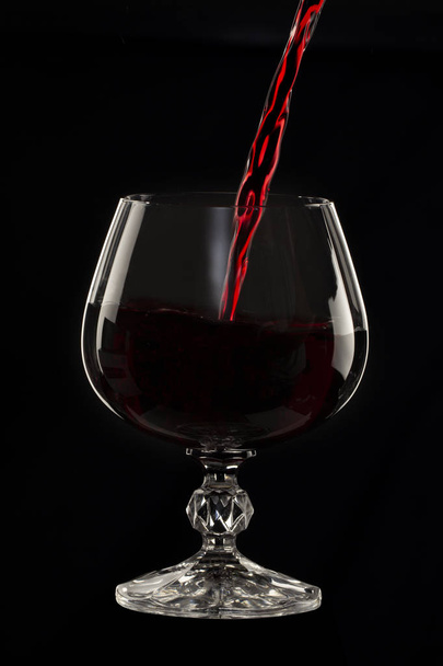 Sklo zátiší obraz A skleničku červeného vína ve skle na černém pozadí zblízka - Fotografie, Obrázek