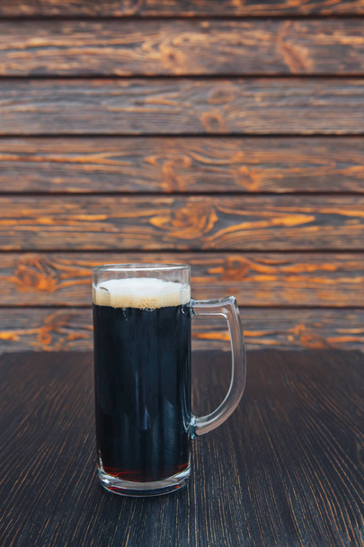 Крупный план стакана тёмного пива на деревянном столе. деревянный фон
 - Фото, изображение