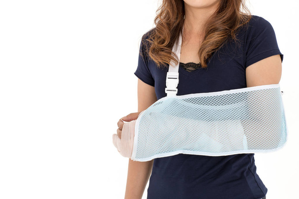 Arm gebroken Aziatische vrouw met arm sling ondersteund op haar hand, concept voor gewond door ongeval en gezondheidszorg. Studio opname op witte achtergrond. - Foto, afbeelding