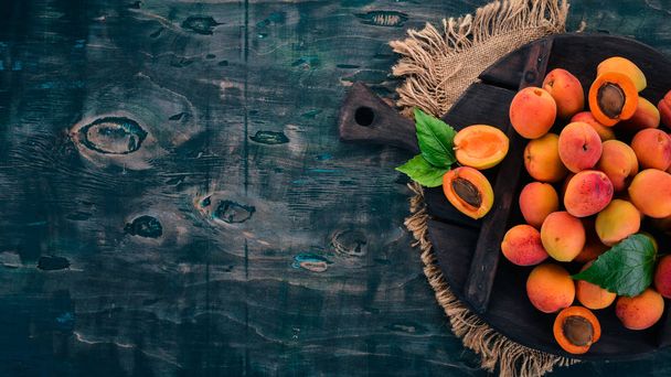 Fresh apricots with leaves On a black wooden background. Top view. Free space for your text. - Foto, afbeelding