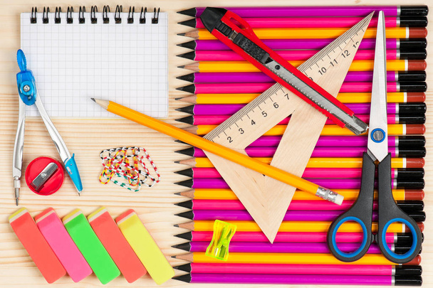 Шкільні аксесуари з барвистими олівцями над дерев'яною поверхнею
 - Фото, зображення