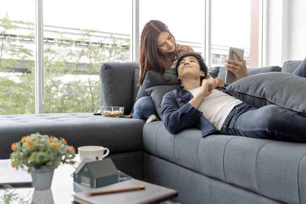 Asiatico adolescente coppia rendere il contatto visivo rilassante su un divano dalla finestra rilassarsi nella lussuosa camera
. - Foto, immagini