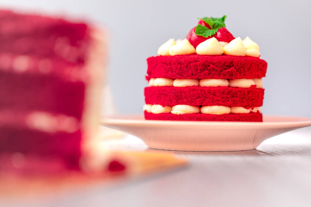 Red velvet cake filled with cream top strawberry and mint leaves. Placed in a beautiful plate on a wooden table. Close up shot - Photo, image