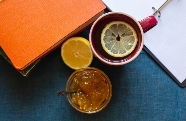 Black Tea with Lemon, Half a Lemon, Books and Lemon Jam  on a Textile  Background. Autumn Concept - Foto, afbeelding