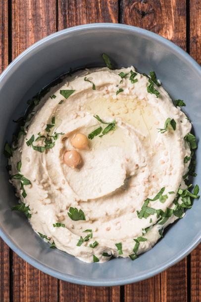 top view of hummus with parsley and chickpeas in bowl on wooden tabletop - Foto, Imagen