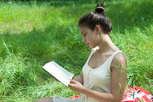 Mädchen liegt auf Plaid im Gras und liest ein Buch - Foto, Bild