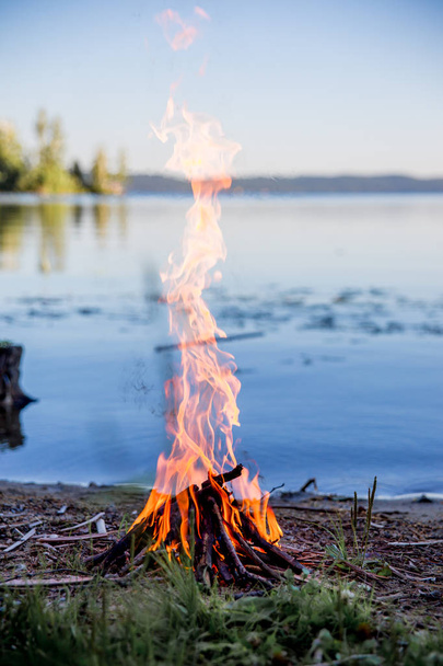 Beautiful campfire in the evening at lake. Fire burning in dusk at campsite - Foto, imagen