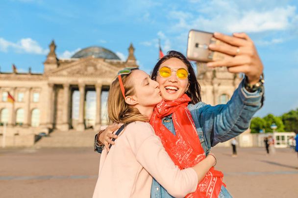 Two happy woman making selfie on background of Reichstag Bundestag building in Berlin. Travel and love concept in Europe - Foto, Imagen