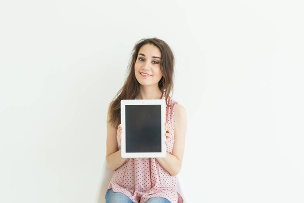 Business, technology and people concept - young woman showing empty screen in tablet on white background - Photo, Image