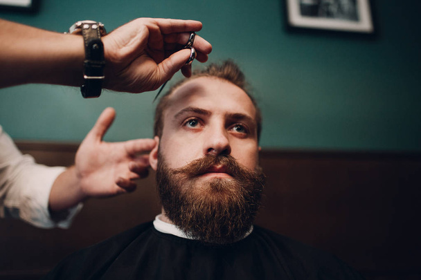 Barbershop with wooden interior. Bearded model man and barber. - Photo, Image