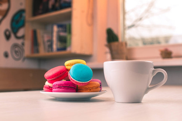 Sweet colorful macarons lie on a plate on the white table. - Fotografie, Obrázek