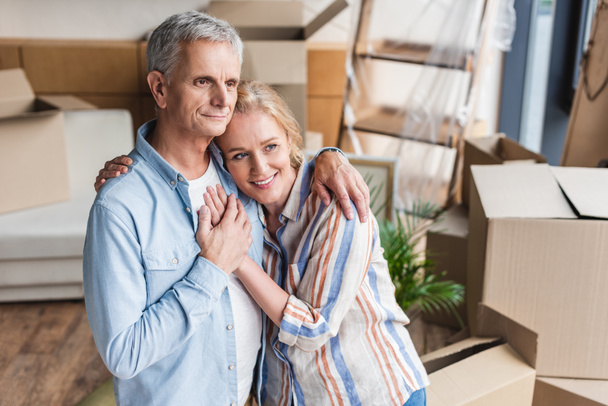 high angle view of happy senior couple embracing and holding hands while moving home - Photo, Image