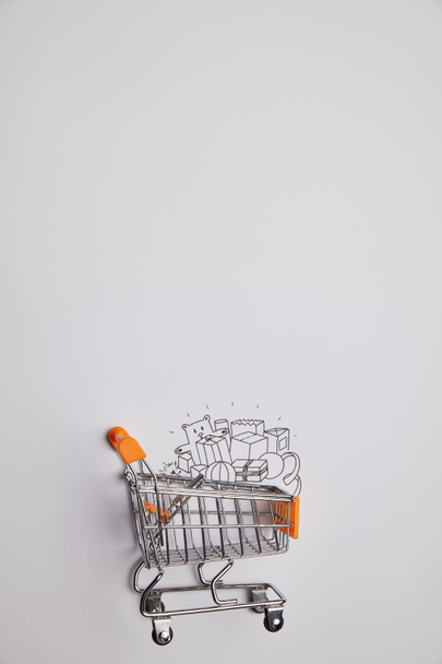 top view of shopping cart with little goods made of paper on grey background - Fotoğraf, Görsel