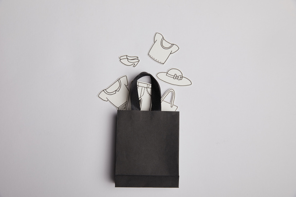 вид на черный торговый мешок и бумажную одежду на сером фоне, концепция покупок
 - Фото, изображение