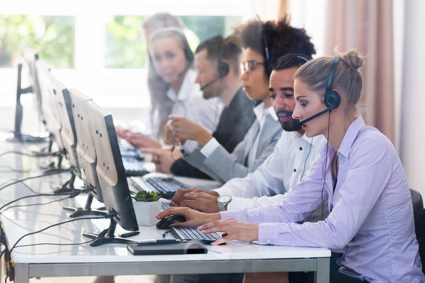 Young Customer Service Executives Using Earphones Working In Call Center - Foto, Imagen