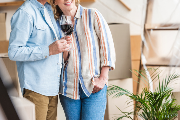 recortado disparo de feliz pareja de ancianos sosteniendo vasos de vino en nuevo hogar
 - Foto, Imagen
