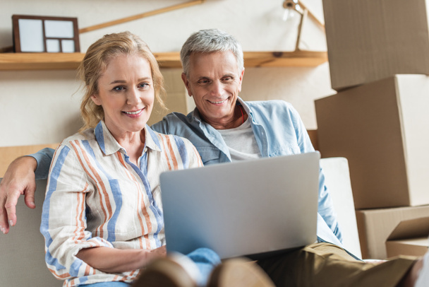 happy senior couple using laptop together during relocation - Photo, Image