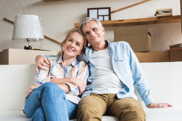 mutlu üst düzey çift birlikte oturan ve yeni evinde kucaklayan - Fotoğraf, Görsel