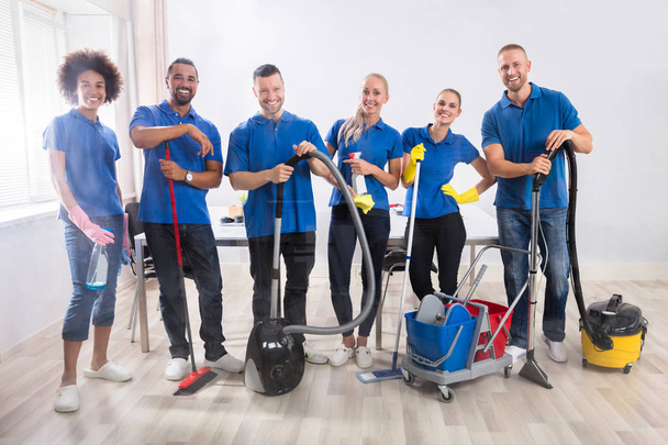 Portrait Of Happy Male And Female Janitors With Cleaning Equipment - Zdjęcie, obraz