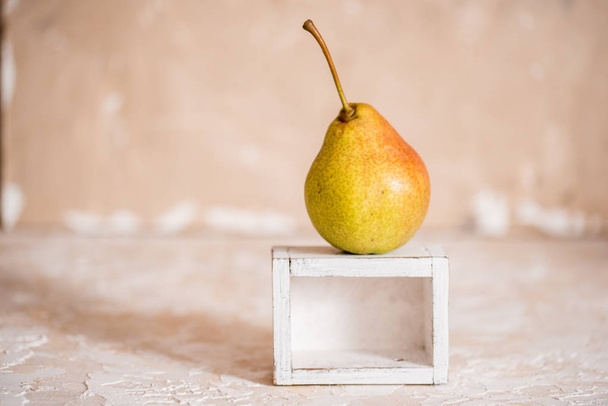 Autumn pear in a white old wooden small box. Life style. Yellow autumn leaves on a concrete light background. Copy space - Foto, immagini