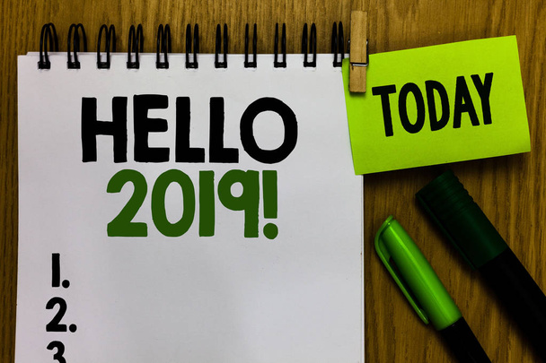 Text sign showing Hello 2019. Conceptual photo expression or gesture of greeting answering the telephone Notebook clothespin holding reminder markers expressing ideas wood table - Photo, Image