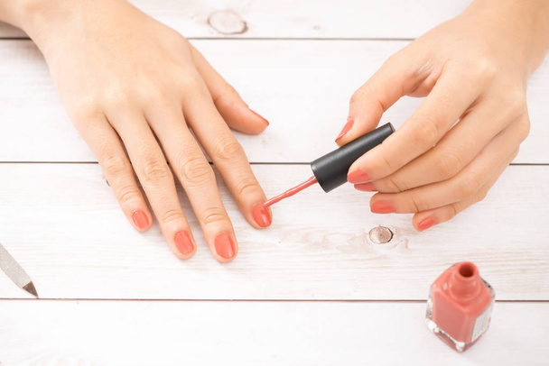 Nail care and manicure. Beautiful female hands applying pink nail polish. - Valokuva, kuva