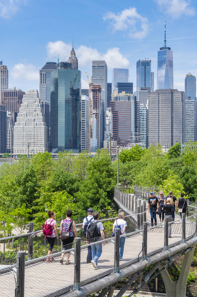 People walking on an walkway towards the Brooklyn Bridge Park in New York City - Foto, imagen