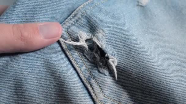 Hand touching ragged jeans. The hole on the blue leaky jeans. - Footage, Video