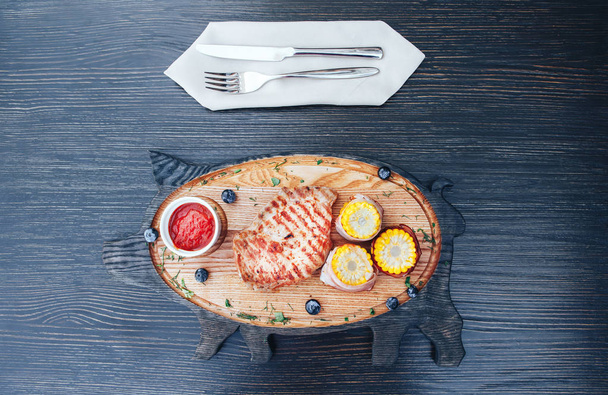 トウモロコシと木製まな板の上のソースと肉のグリル。木製の背景。トップ ビュー - 写真・画像