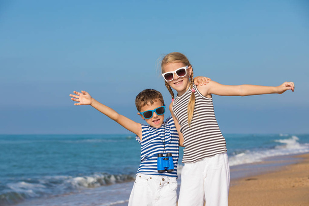 Dos niños pequeños y felices jugando en la playa durante el día. Están vestidos con chalecos de marinero. Niños divirtiéndose al aire libre. Concepto de marineros de vacaciones y familia amigable
. - Foto, Imagen