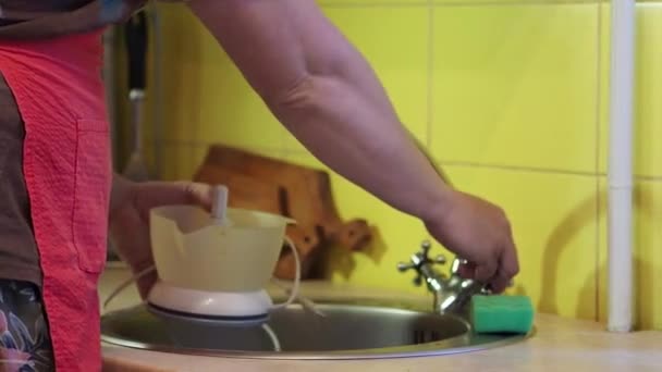 The man washes the juice extractor. - Video