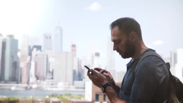 Sikeres fiatal üzletember használ smartphone app epikus Manhattan pénzügyi központ skyline, New York City bevásárló. - Felvétel, videó